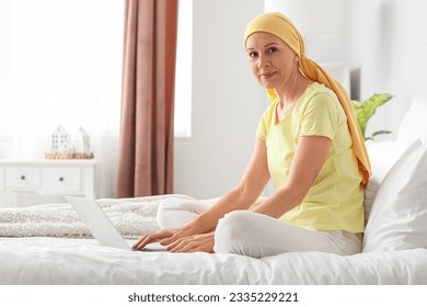 Mature woman after chemotherapy using laptop in bedroom - Powered by Shutterstock