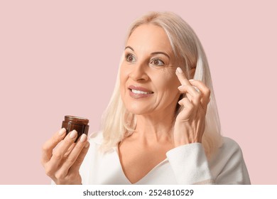 Mature woman applying cream under her eyes against color background, closeup - Powered by Shutterstock