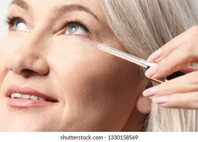 Mature Woman Applying Face Serum, Closeup