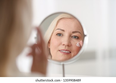 Mature Woman Applying Facial Cream At Home