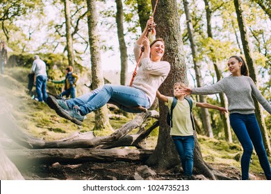 Mature woman is being pushed on a rope swing by her children while they are out on a hike.  - Powered by Shutterstock