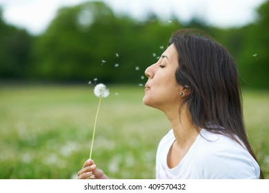 Mature Woman Blowing Dandelion Flower