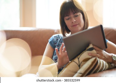 Mature Woman Browsing The Internet On A Digital Tablet