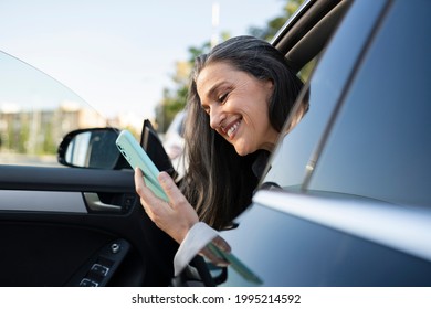 Mature Woman, Businesswoman Getting Out Of Car Using Smartphone