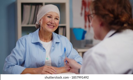 Mature Woman With Cancer Visiting Doctor In Hospital Listening About Recovery. Back View Of Oncologist Telling Good News To Patient After Chemotherapy