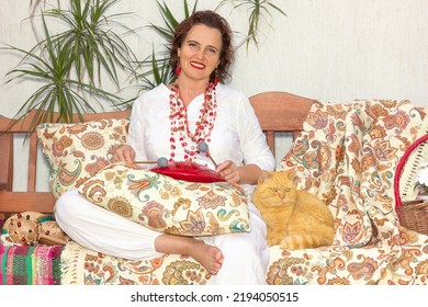 A Mature Woman With A Cat And A Glucophone Is Resting On A Bench Outdoors.