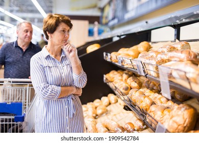 mature woman choosing bread and baking in grocery section of supermarket - Powered by Shutterstock