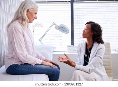 Mature Woman In Consultation With Female Doctor Sitting On Examination Couch In Office