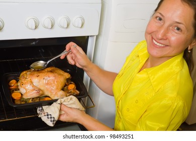 Mature Woman Cooking Stuffed Chicken On Pan In Oven