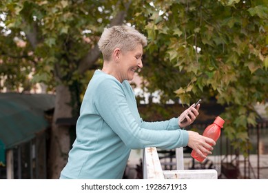 Mature Woman Cooling Down After Jogging And Using Phone