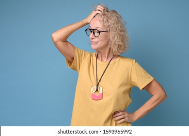 Mature Woman With Curly Hair In Yellow Clothes Thinking About Her Life Problems Being Sad And Confused. Studio Shot