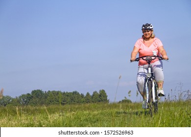 Mature Woman Cycling Through Field