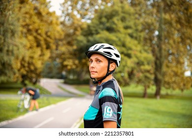 Mature Woman Cyclist In Sports Clothes With Cycling Helmet In The Green Park. Copy Space