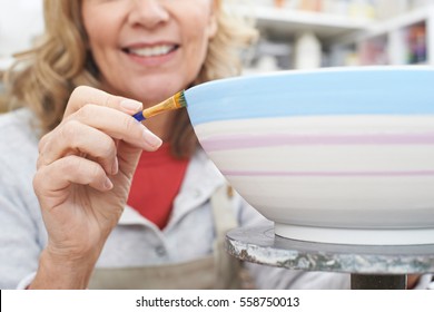 Mature Woman Decorating Bowl In Pottery Class