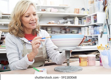 Mature Woman Decorating Bowl In Pottery Class