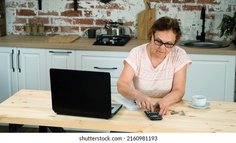 Mature Woman Distributing Budget by Counting Money, Calculating Expenses and Savings on a Calculator and Taking Notes. Economic Crisis and Financial Difficulties Concept