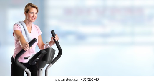 Mature Woman Doing Exercise On Elliptical Trainer.