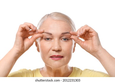 Mature woman doing face building exercises against white background