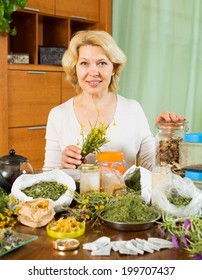 Mature Woman Doing Herbal Tea And Smiling At Home  