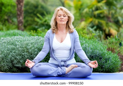 Mature Woman Doing Lotus Yoga Position Outside In The Garden