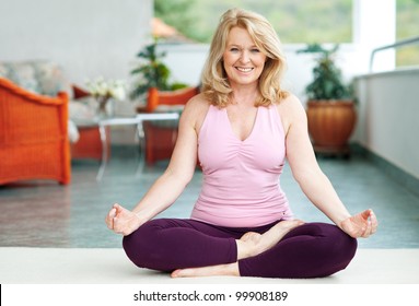 Mature Woman Doing Lotus Yoga Position On Her Home Balcony