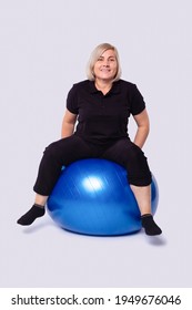 Mature Woman Doing Yoga At Home On A Blue Ball. He Spends His Time At Home. High Quality Photo