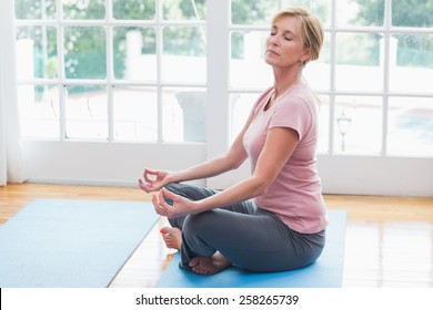 Mature Woman Doing Yoga On Fitness Mat At Home In The Living Room