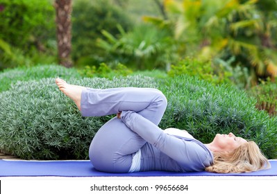 Mature Woman Doing Yoga Position Outside In The Garden