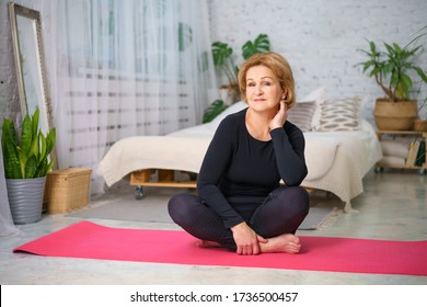 Mature woman doing yoga sitting on the Mat at home, healthy lifestyle concept sitting at home. - Shutterstock ID 1736500457