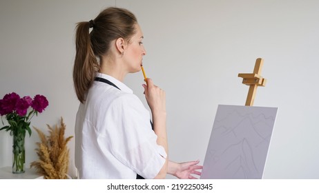 Mature Woman Draws Future Sketch Of Landscape On Easel. Skilled Artist Thinks About Picture With Concerned And Thoughtful Expression Closeup