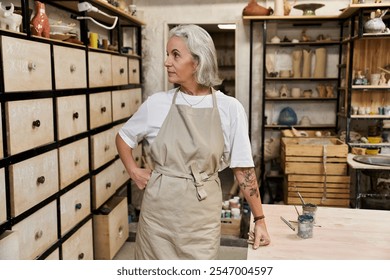 The mature woman, dressed in an apron, prepares to begin her creative work in a serene studio. - Powered by Shutterstock