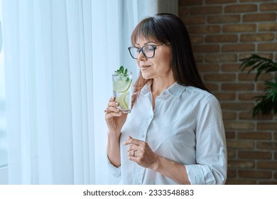 Mature woman with drink, mineral water with lemon mint ice - Powered by Shutterstock