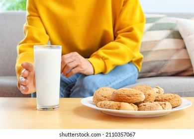 Mature Woman Drinking Milk And Eating Cookies At Home