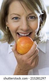 Mature woman eating apple, close-up, front view, portrait