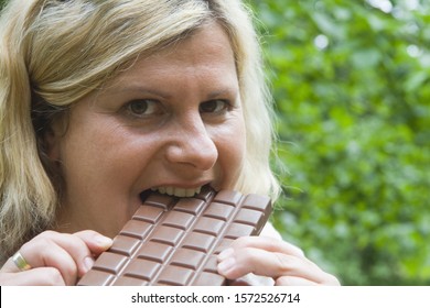 Mature Woman Eating Chocolate Bar, Smiling