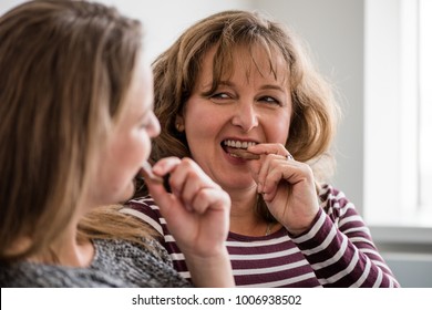 Mature Woman Eating Chocolate At Home With Daughter