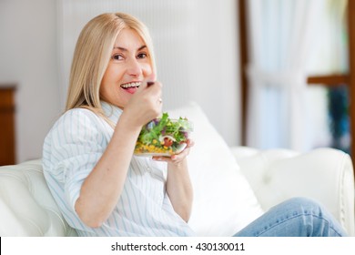 Mature Woman Eating A Healthy Salad On Her Sofa