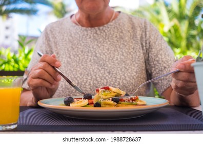 Mature Woman Eating Healthy Summer Breakfast, Classic American Pancakes With Banana, Kiwi, Fresh Berry And Honey