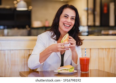 Mature Woman Eating Natural Snack With Strawberry Juice At Bakery