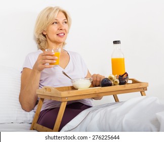 Mature Woman Eating Orange Juice, Berries And Yogurt At Overbed Table In Bed