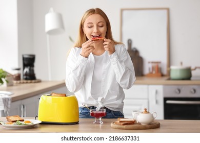 Mature Woman Eating Tasty Toasts In Kitchen