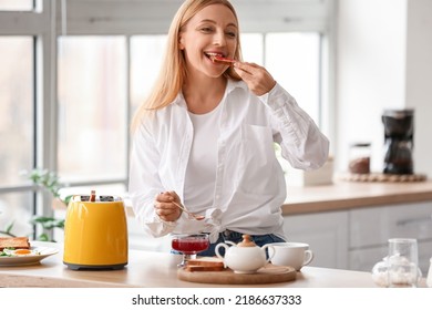 Mature Woman Eating Tasty Toasts In Kitchen