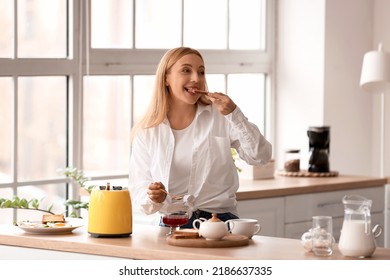 Mature Woman Eating Tasty Toasts In Kitchen