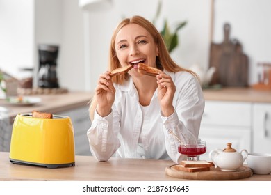 Mature Woman Eating Tasty Toasts In Kitchen