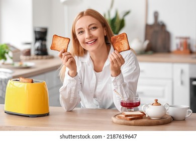 Mature Woman Eating Tasty Toasts In Kitchen