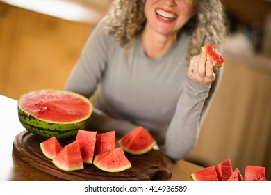 Mature Woman Eating Watermelon In Kitchen