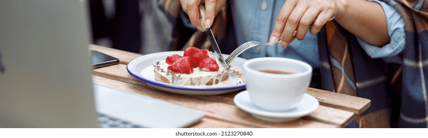 Mature woman eats tasty toast with cut strawberries and cream near laptop and cup of coffee at table on outdoors cafe terrace closeup - Powered by Shutterstock