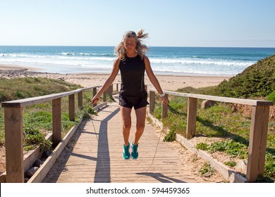 Mature Woman Exercising Jumping Rope At The Beach