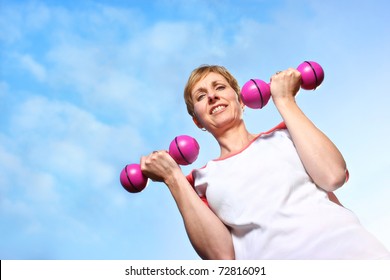 Mature Woman Exercising Outdoors, Doing Dumbbell Curls In The Fresh Air