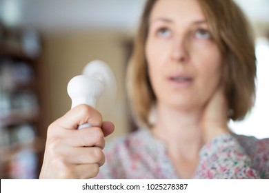 Mature Woman Experiencing Hot Flush From Menopause Using Electric Fan